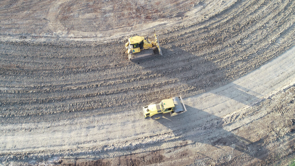 Two yellow excavators are shown on an earthworks plant, of what would’ve been contaminated land before and has now been reshaped for future development projects such as housing.